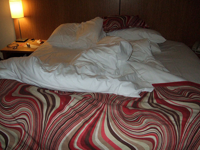 Unmade bed with patterned blanket symbolizing turbulent friendship realization