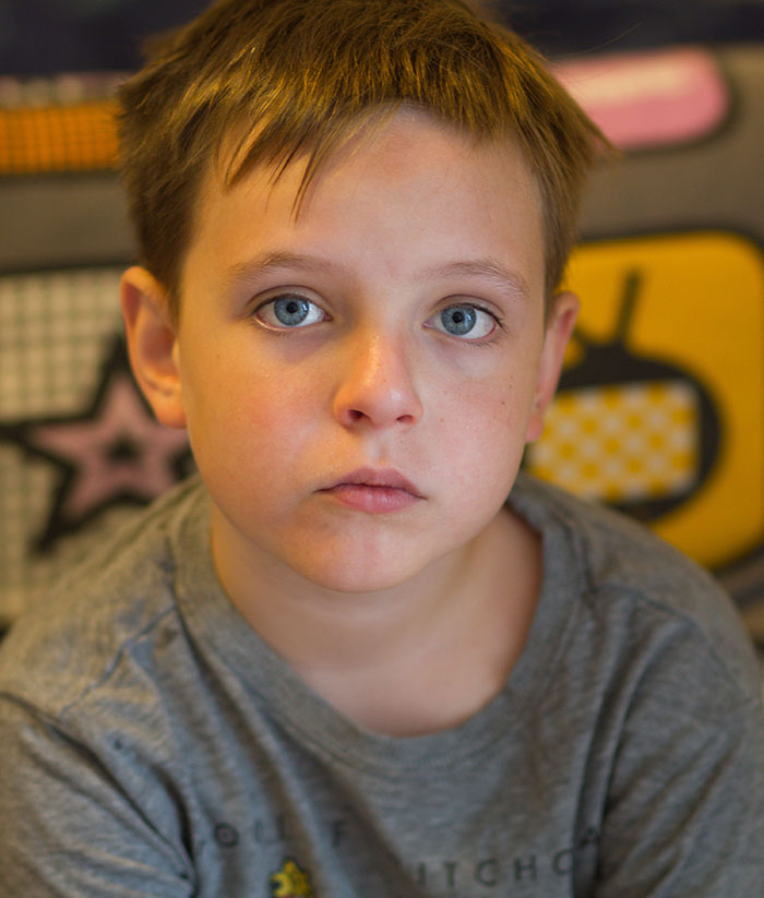 Serious young boy with blue eyes staring ahead revealing friend insights