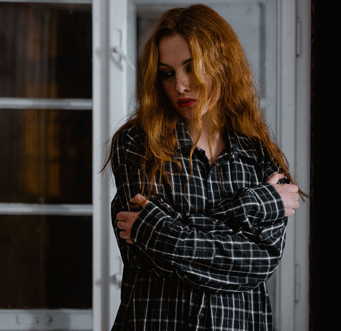 Sad woman with red hair embracing herself sharing friend realization