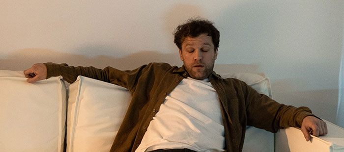 Man overwhelmed on couch after realizing fake friend truth
