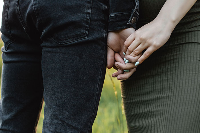 Couple holding hands closely in a field showing friendship bond
