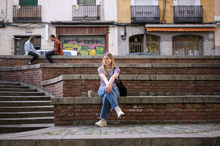 Woman sitting alone looking sad near urban stairs
