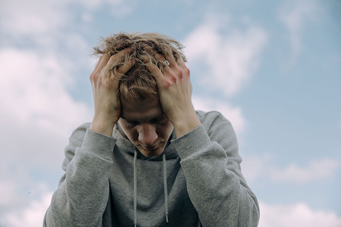 Stressed young man holding head reflecting on friendship realization