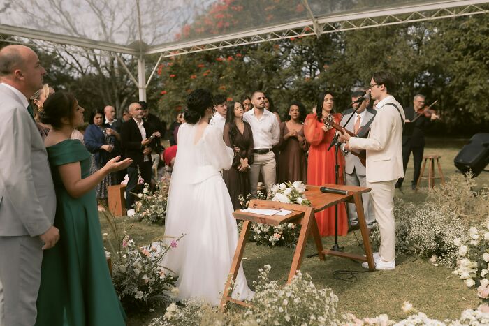 Wedding guests watching the couple during an outdoor ceremony under a tent