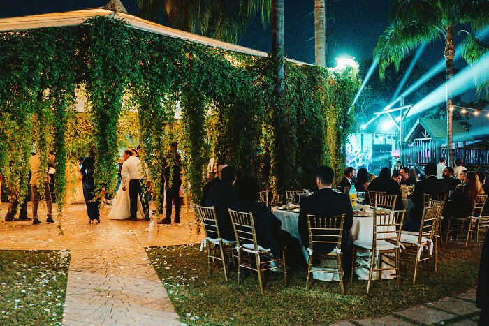 Outdoor wedding reception with guests seated near leafy vines