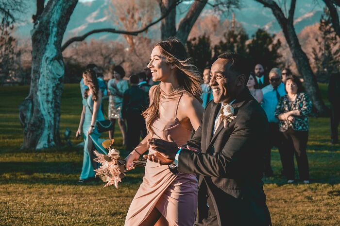 Happy wedding guests walking outdoors in formal attire