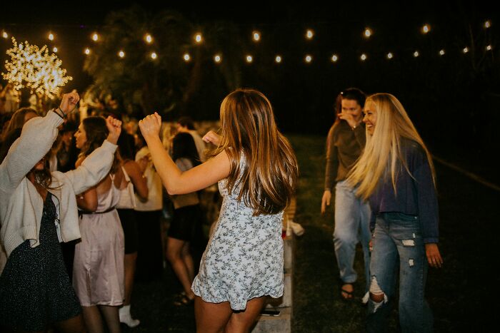 Guests dancing at outdoor wedding party under string lights