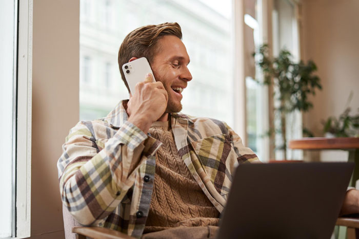 A smiling man on a phone call, using a laptop, representing the guy who wants his name on author GF's book.