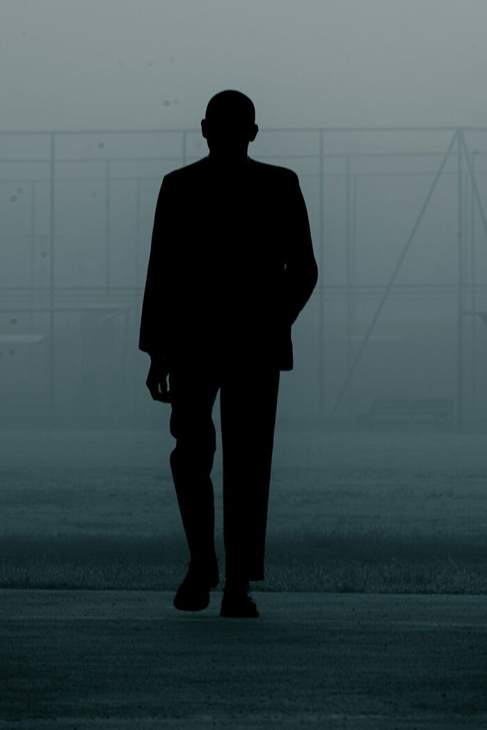 A dark silhouette of a man walking through a foggy, desolate outdoor area, a visual representation of unsolved mysteries.