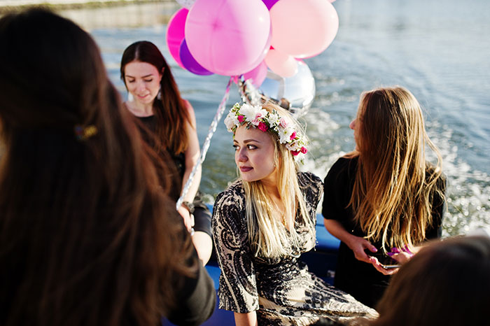 A group of women on a boat with balloons, one wearing a flower crown, during a bachelorette party for a sister marrying into a racist family. A group of women on a boat with balloons, one wearing a flower crown, during a bachelorette party for a sister marrying into a racist family.
