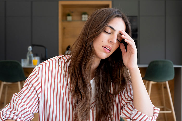 A distraught woman, upset about her sister marrying into a racist family, holding her forehead in a modern kitchen. A distraught woman, upset about her sister marrying into a racist family, holding her forehead in a modern kitchen.