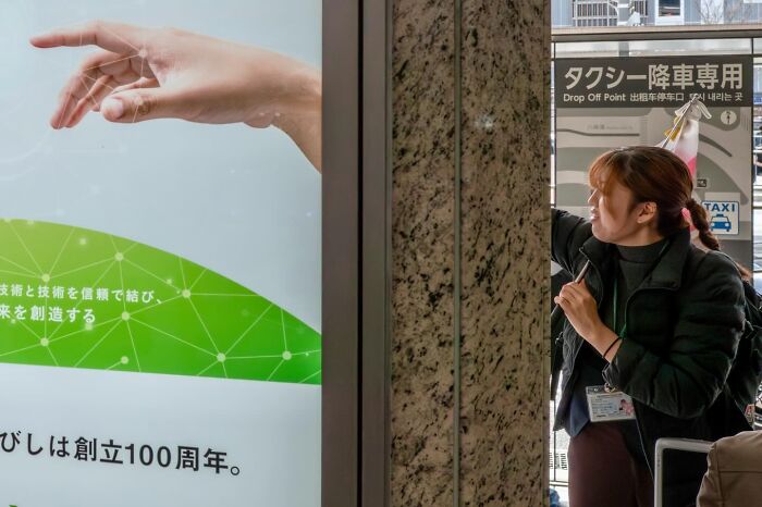 Street coincidence: A woman appears to be interacting with a hand from a billboard, caught by Edas Wong.