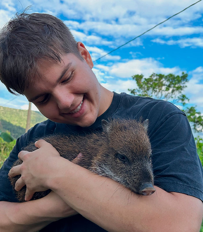 Man embracing a small peccary, illustrating the bond with a remote tribe and Amazonian life. Man embracing a small peccary, illustrating the bond with a remote tribe and Amazonian life.