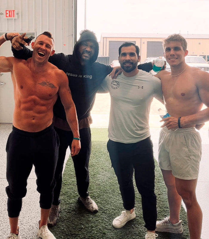 Christian men in a men-only gym, smiling and flexing, promoting faith and fitness.