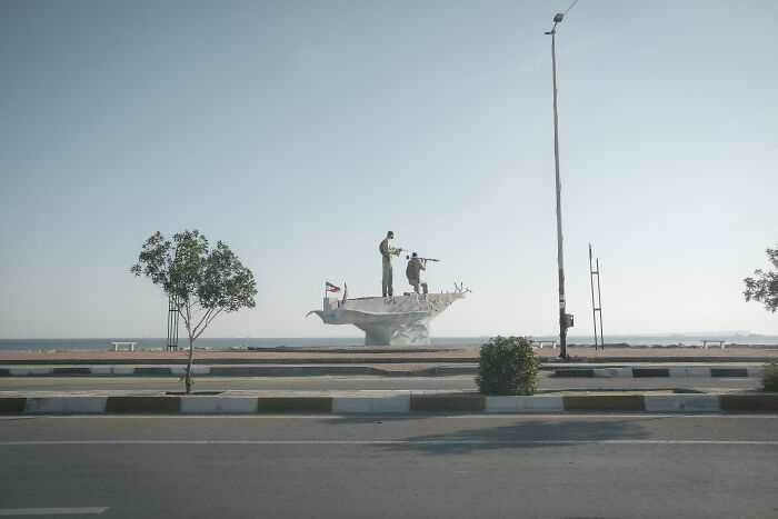 A monument depicting figures on a boat by the Strait of Hormuz, symbolizing the human aspect of the area.
