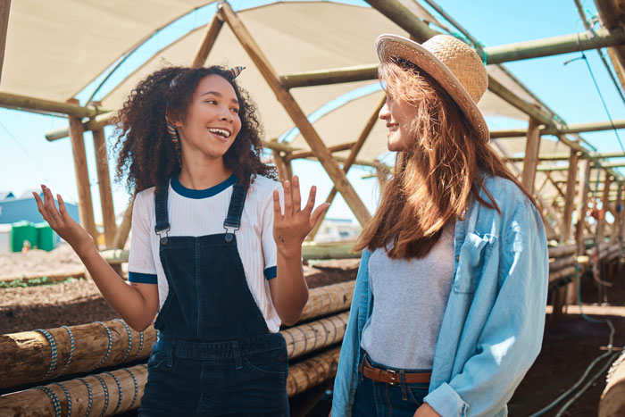 Two women discussing a brownie recipe, one with curly hair gesturing, the other in a hat, for petty payback. Two women discussing a brownie recipe, one with curly hair gesturing, the other in a hat, for petty payback.