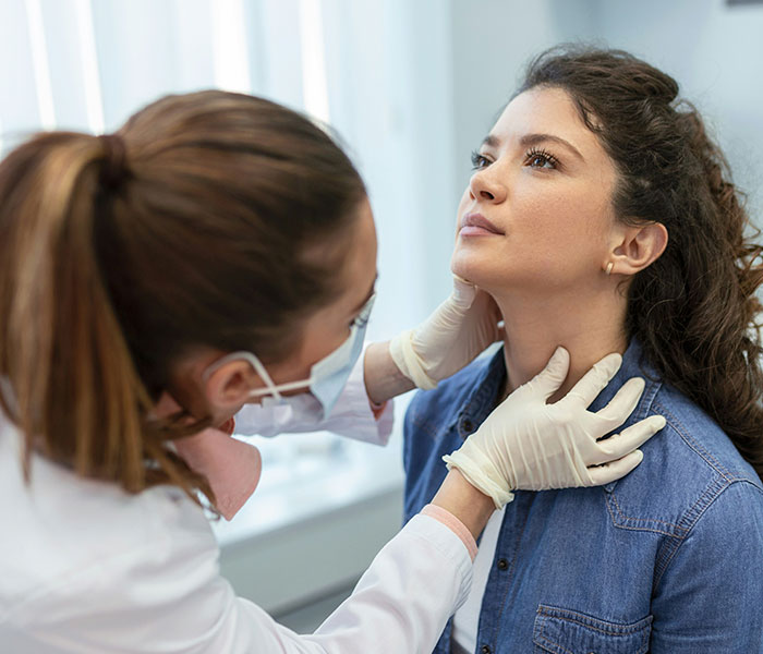 Doctor checking a woman's neck for cancer symptoms, emphasizing early detection over normal aging or stress dismissal. Doctor checking a woman's neck for cancer symptoms, emphasizing early detection over normal aging or stress dismissal.