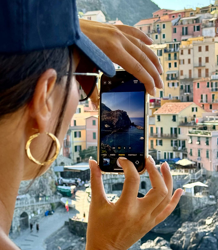American tourist taking a photo with a smartphone, capturing a picturesque European town, showing typical tourist outfits.