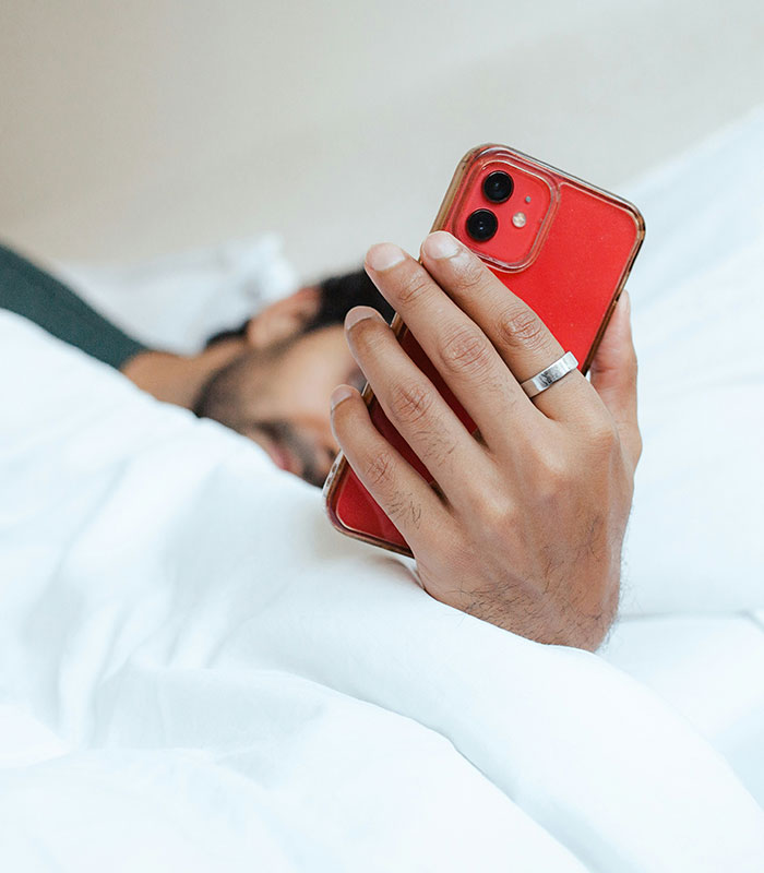 Man in bed checking phone. Morning habits like checking your phone can quietly damage your health and impact cortisol. Man in bed checking phone. Morning habits like checking your phone can quietly damage your health and impact cortisol.