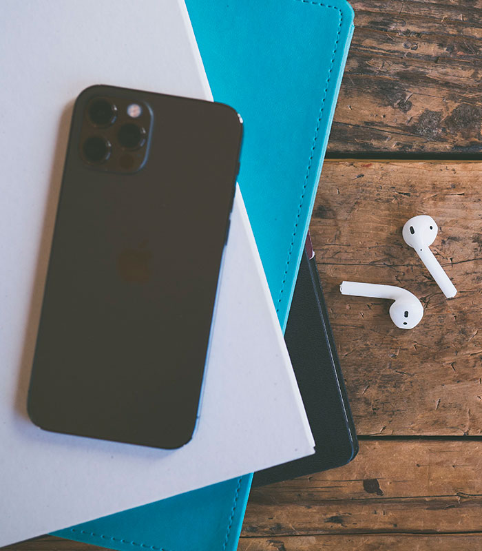An iPhone and AirPods resting on notebooks, representing modern communication in a public space. An iPhone and AirPods resting on notebooks, representing modern communication in a public space.