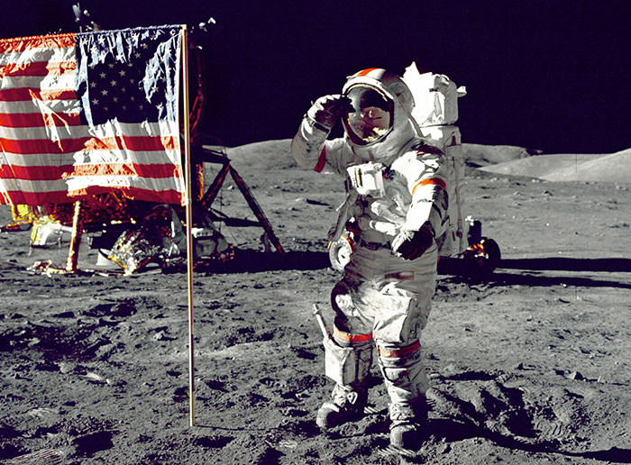 An astronaut saluting the American flag on the moon's surface, part of the NASA photos questioned for hidden alien presence.