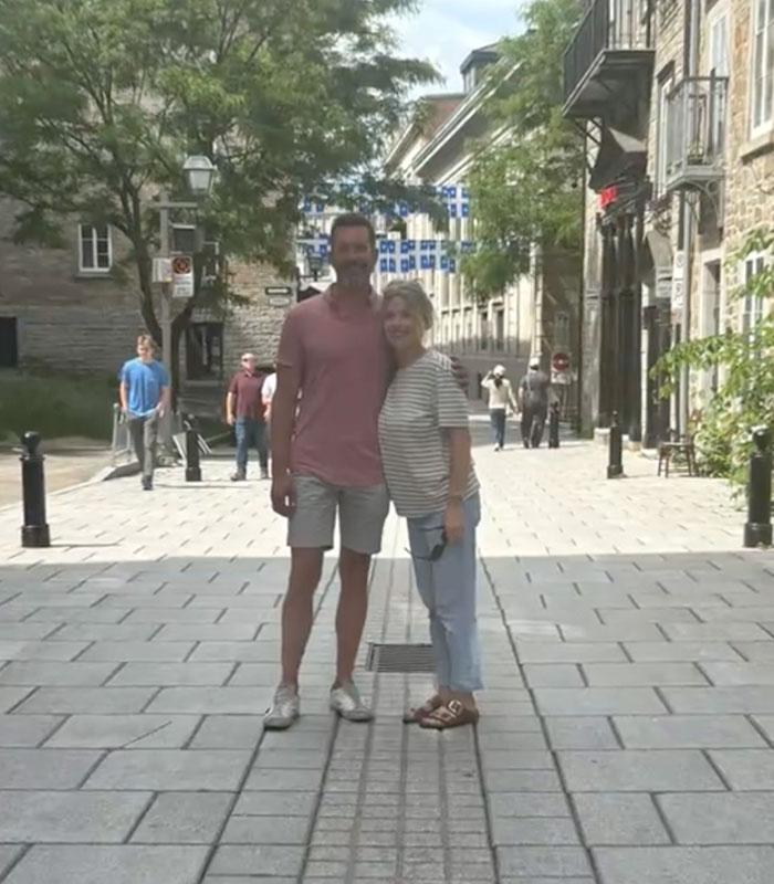 Grieving father's son-in-law and wife posing in a city street, amidst surfacing chilling details. Grieving father's son-in-law and wife posing in a city street, amidst surfacing chilling details.