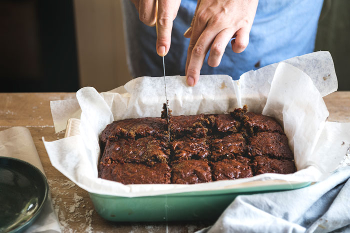Woman cutting delicious brownies to serve teammates, keeping the recipe secret as petty payback. Woman cutting delicious brownies to serve teammates, keeping the recipe secret as petty payback.