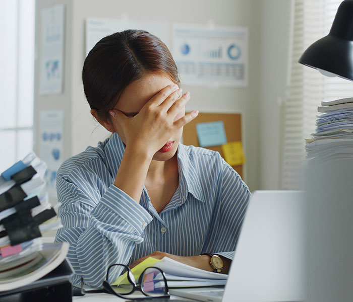 Woman at desk, showing signs of stress or fatigue, potentially dismissing cancer symptoms as normal aging or stress. Woman at desk, showing signs of stress or fatigue, potentially dismissing cancer symptoms as normal aging or stress.