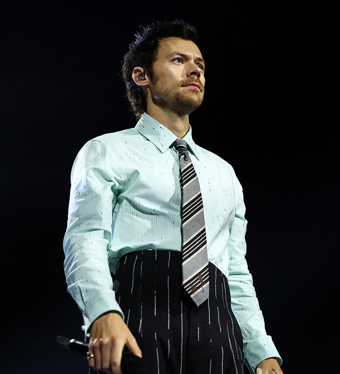 Harry Styles performs on stage in a mint green shirt and striped tie, a moment captured before his wardrobe malfunction. Harry Styles performs on stage in a mint green shirt and striped tie, a moment captured before his wardrobe malfunction.