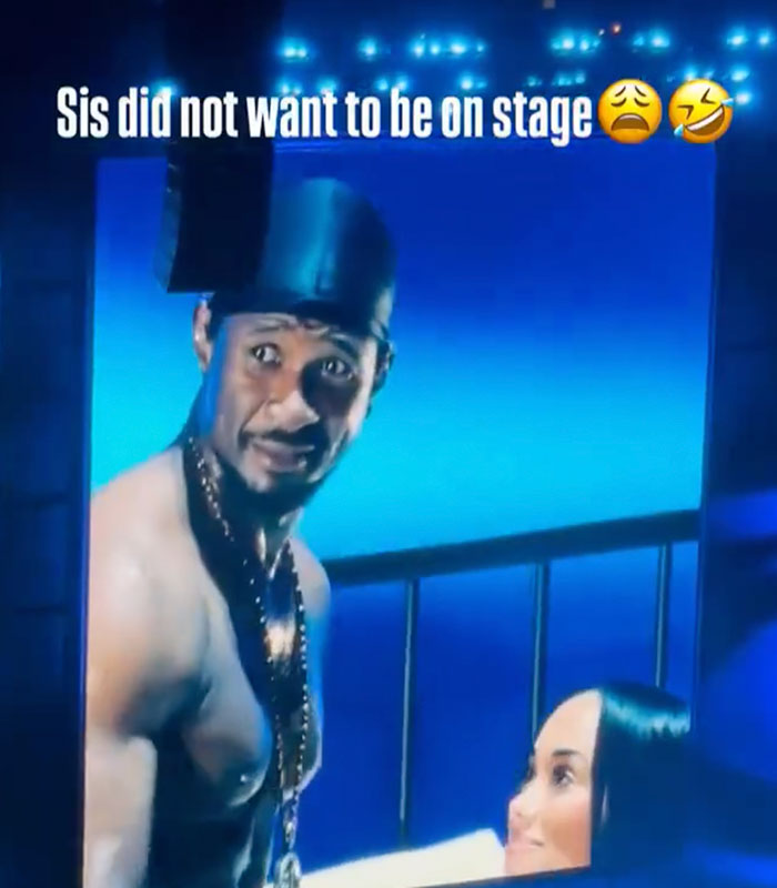 Usher looking at a woman on stage, showing her awkward reaction to his seductive moves.