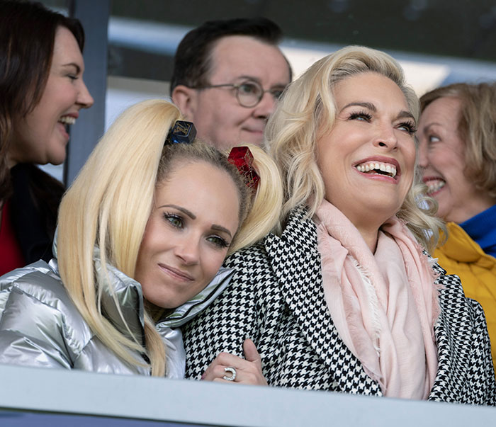 Two women smiling in a crowd, part of the discourse on beauty standards and heavy photoshop in TV.