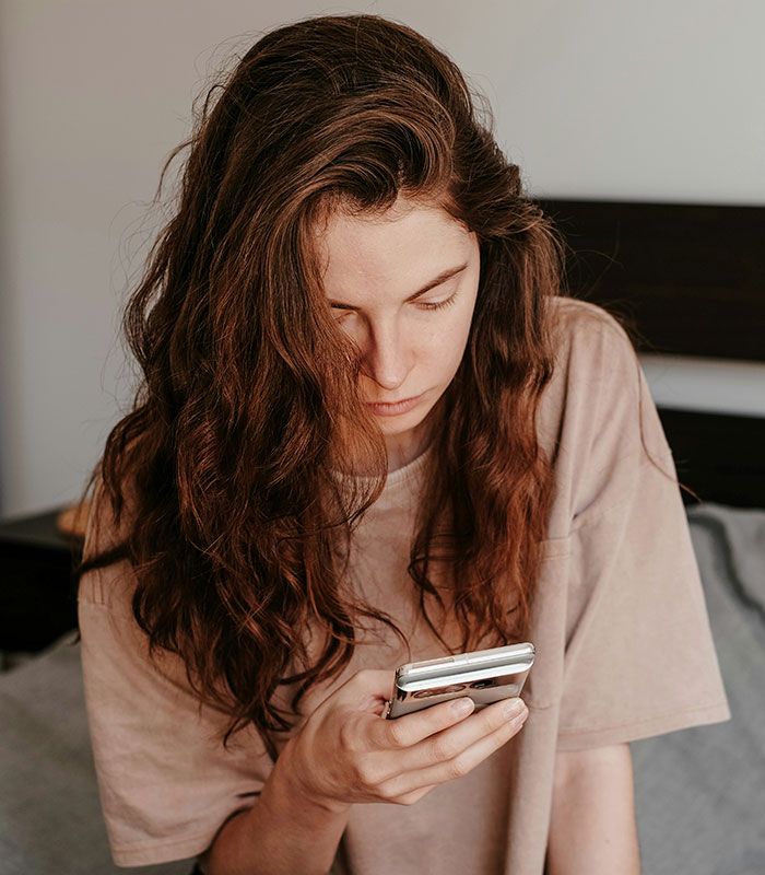 Woman in bed looking at her phone. Her morning habits could be quietly damaging her health and elevating cortisol. Woman in bed looking at her phone. Her morning habits could be quietly damaging her health and elevating cortisol.