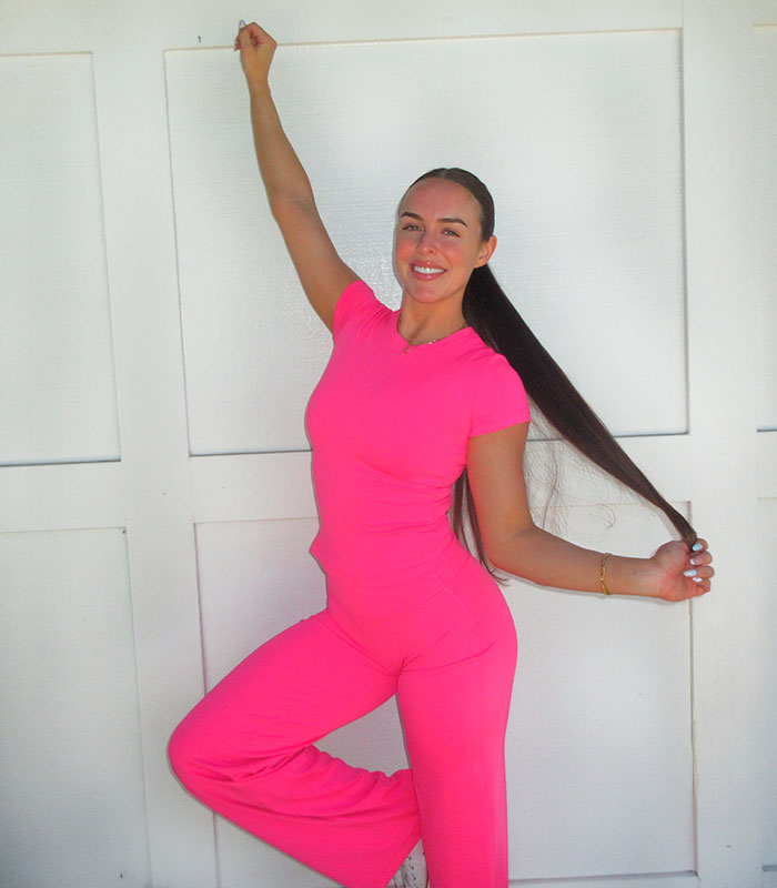 A woman in a vibrant pink gym outfit smiles, showing confidence after a successful gym workout.