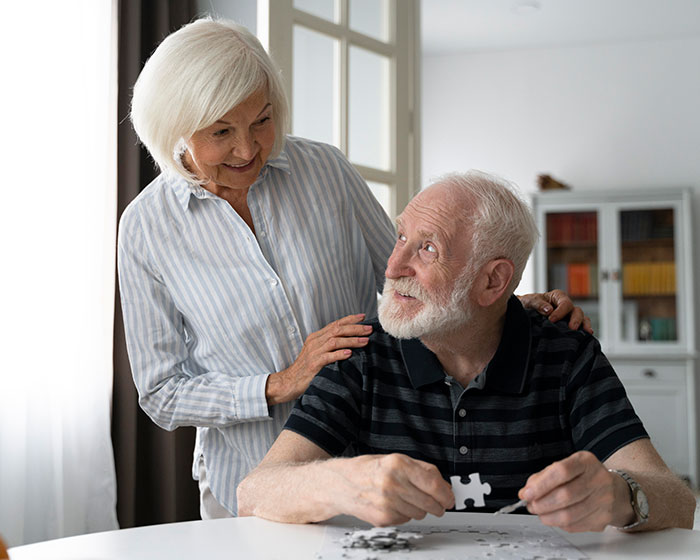 Happy elderly couple doing a puzzle together, reducing risk of dementia for married people.