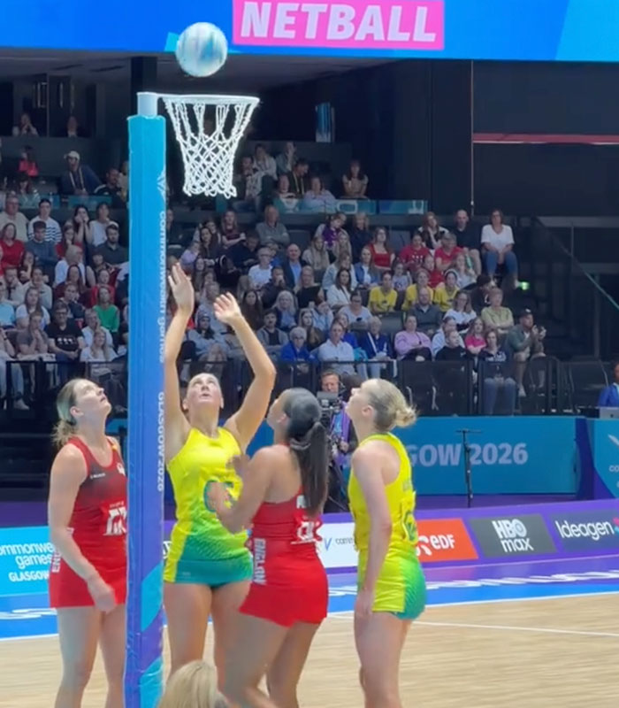 Female Australian team netball player attempting to score during the Commonwealth Games, focusing on the wardrobe.