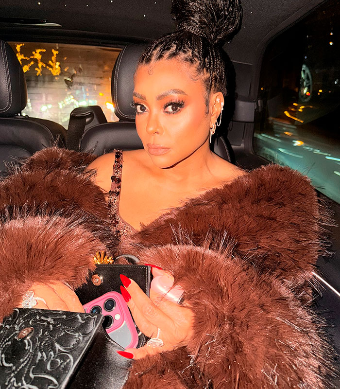 Taraji P. Henson in a brown faux fur coat, revealing a dress with extreme cleavage in a car.