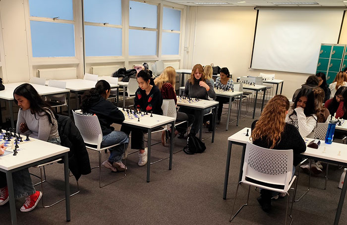 All-female chess community team playing intently at multiple tables during a chess tournament. All-female chess community team playing intently at multiple tables during a chess tournament.