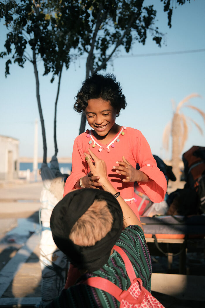 A joyful young girl playing with an adult near the Strait of Hormuz, highlighting the human side of the region.