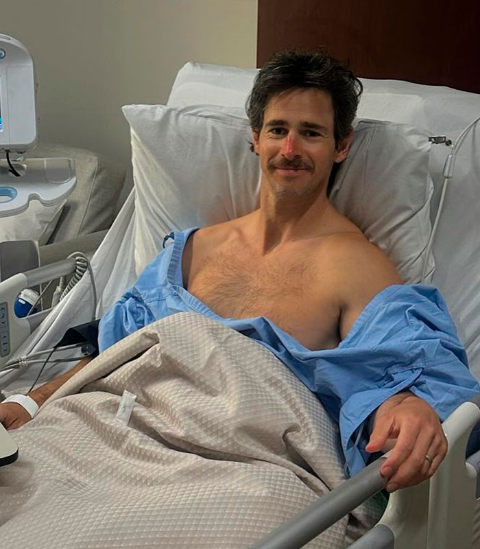 A man with hypospadias smiling in a hospital bed, recovering from surgery.