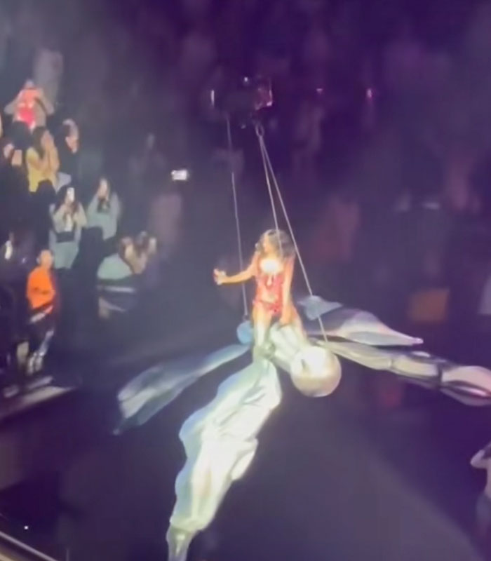 Katy Perry performing a bizarre stunt, suspended high above a stage during her show.