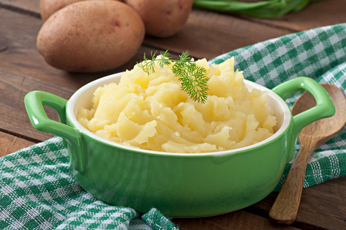 A vibrant green bowl of fluffy mashed potatoes, garnished with fresh dill, ready for Thanksgiving dinner. A vibrant green bowl of fluffy mashed potatoes, garnished with fresh dill, ready for Thanksgiving dinner.