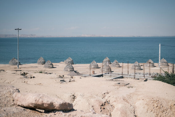 Huts on a sandy beach next to the Strait of Hormuz, showcasing the human side of this geopolitical hotspot.