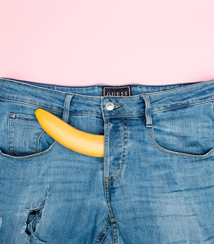 A banana protruding from the fly of a pair of jeans, symbolizing struggles of hypospadias affecting men.