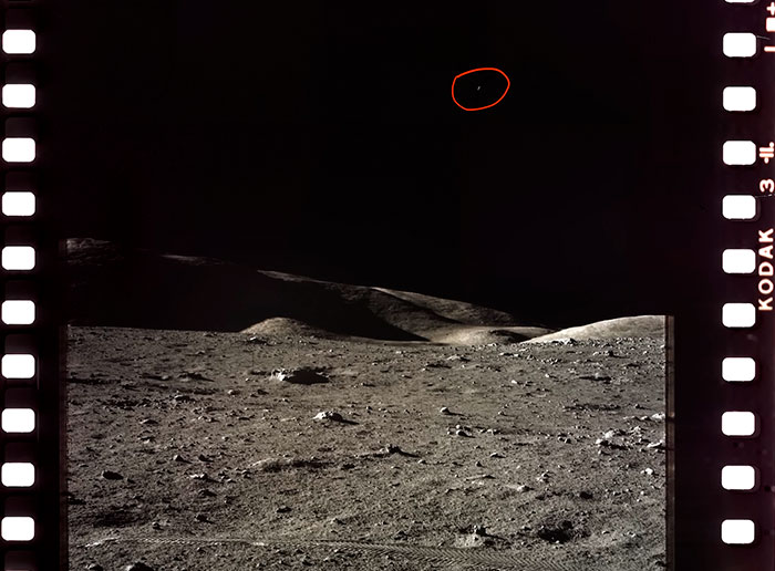 NASA photo of a lunar landscape with a small, circled object in the dark sky, suggesting an alien presence.