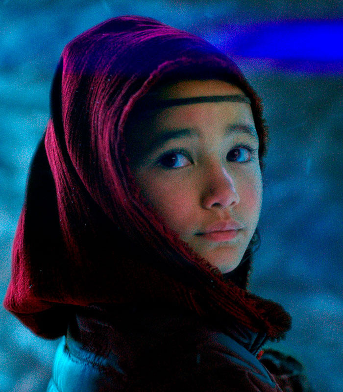 Godzilla actress Kaylee Hottle, wearing a red hood, looks over her shoulder, blue light illuminating her face. Godzilla actress Kaylee Hottle, wearing a red hood, looks over her shoulder, blue light illuminating her face.