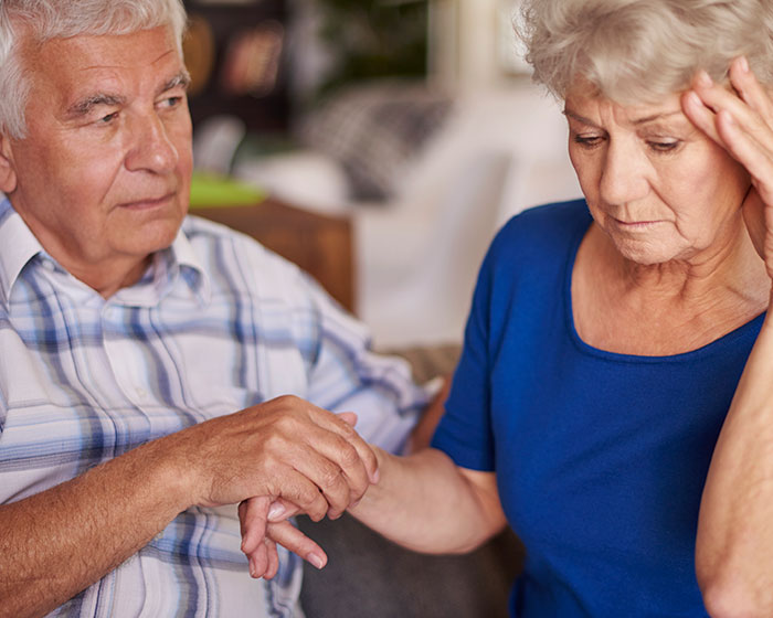 An elderly man comforting an elderly woman, suggesting the emotional impact on married people developing dementia.