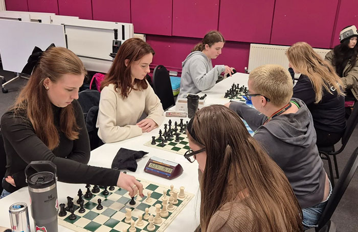 An all-female chess team focuses on their moves during a competitive match, showcasing their strategic skills. An all-female chess team focuses on their moves during a competitive match, showcasing their strategic skills.