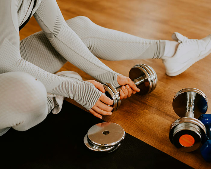 A woman holding a dumbbell, representing fitness and how body fat percentages can transform the face. A woman holding a dumbbell, representing fitness and how body fat percentages can transform the face.