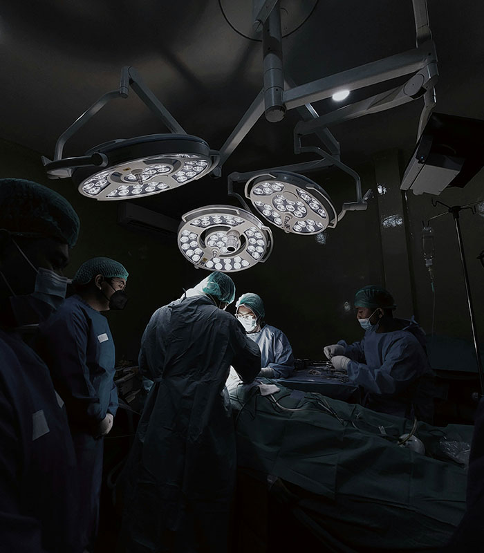 Surgeons performing an operation in a brightly lit operating room, addressing the disease hypospadias.