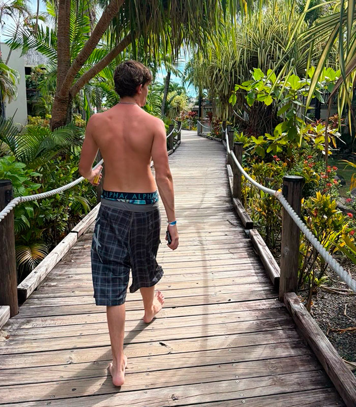 Teen son walking on a boardwalk in a tropical setting, reflecting his travel before facing Thai jail over airport crime.